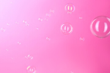 Beautiful transparent soap bubbles on pink background