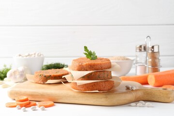 Uncooked carrot cutlets and ingredients on white wooden table. Vegetarian product