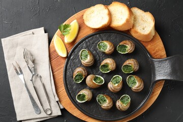 Delicious cooked snails served on grey textured table, flat lay