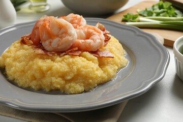 Plate with fresh tasty shrimps, bacon, grits and green onion on white table, closeup