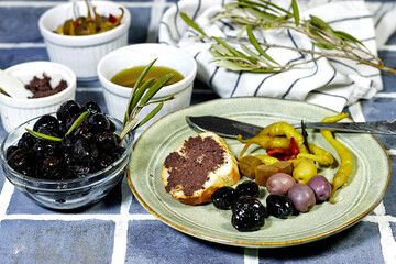 Tapenade - paste made from olives. Bowls with spreadable black and green olive cream and oil on tiles background