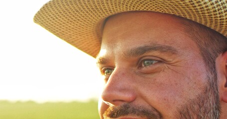 Cropped portrait of the thoughtful farmer looking away. Senior farmer smiling. Slow motion. Close up of the caucasian good looking young man with a beard smiling while looking at the field