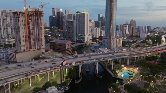 Aerial view of vehicles driving on Downtown I95 Riverside multilane highway at sunset with Miami skyline view. Drone flight over multi-level intersection Miami Florida