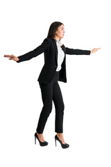 A woman in business attire performing a balancing act with outstretched arms on a white background, conveying a concept of balance