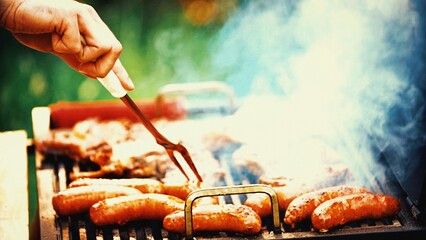 Sizzling BBQ: Closeup of Unrecognizable Person Flipping Meat and Sausages on Grill, Ready for...