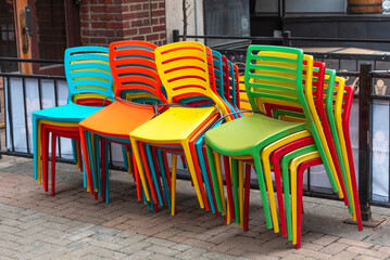 Colorful chairs stacked in an outdoor enclosed restaurant.

