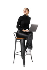 A smiling woman seated on a stool, using a laptop, isolated on a white background, depicting a...