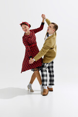 Elegant, charming young couple, man and woman in retro style clothes dancing isolated over white...