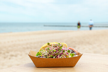 fish roll in sandwich box on a table on a beach. fillings in paper ecological boxes craft....