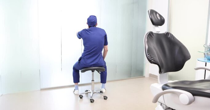  Sitting dentist, dealing with neck pain.Symptoms and self help exercises, stretching. Back view.