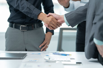 Two businessmen are shaking hands in office while sitting at the desk, Business people concept