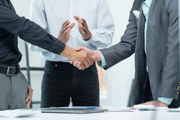Two businessmen are shaking hands in office while sitting at the desk, Business people concept