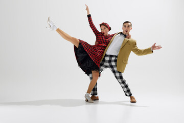 Playful moment captured between a dancing couple, young handsome man and beautiful woman energetically dancing isolated over white studio background. Concept of art, retro and vintage, entertainment