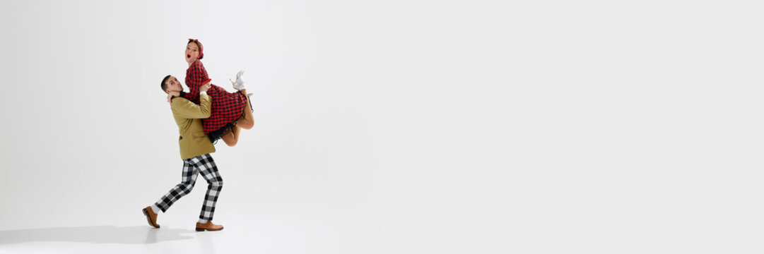 Dynamic image of stylish young couple, man and woman in retro themed clothes dancing isolated over white studio background. Concept of art, retro and vintage, hobby, entertainment, 20s. Banner