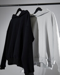 Two sweatshirts in neutral colors hang on a hanger