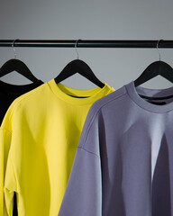 three colored T-shirts hanging on hangers