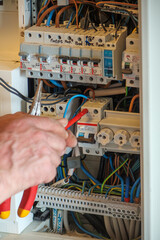 An electrician works on a fuse box