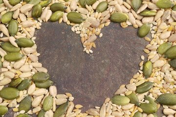 Sunflower, pumpkin, sesame, golden linseed seeds mix. Top view. With a heart-shaped copy space....