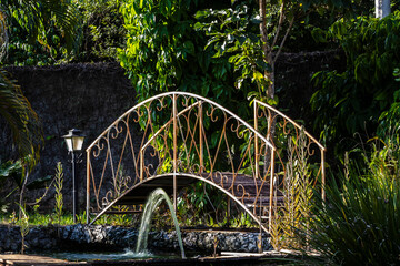 Garden with arch-shaped iron bridge and water fountain on a public park in Brazil