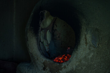 A dark, smoky oven with a hole in the middle. The hole is filled with glowing coals