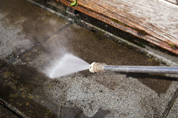 Concrete tile cleaning with pressure washer. Close up of high pressure water jet. Patio, balcony or...