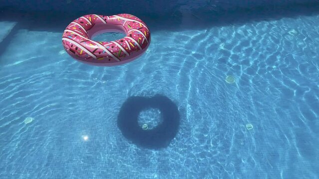 An inflatable donut floating in a blue pool, calm and tranquility