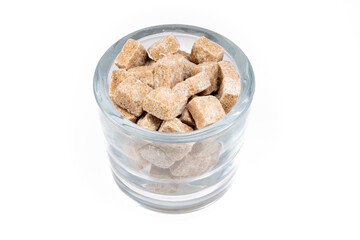 A glass full of brown cane sugar cubes
