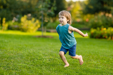 Adorable little boy having fun outdoors on sunny summer day. Kid running outdoors. Child exploring nature. Summer activities for kids.