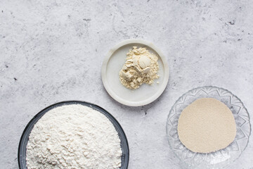 Mise en place of ingredients for making bread, All purpose flour vital wheat gluten and yeast on a marble countertop, process of making bread