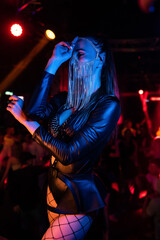 Portrait of a beautiful go-go dancer posing in a nightclub wearing a mask on her face. Blue...