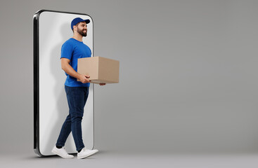 Courier with parcel walking out from huge smartphone on grey background. Delivery service. Space...