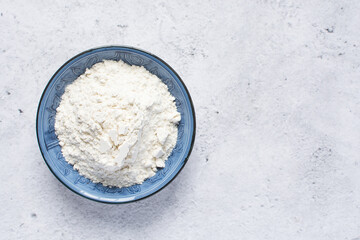 All purpose flour in a silver shaped measuring cup, one cup of flour in a metal measuring cup