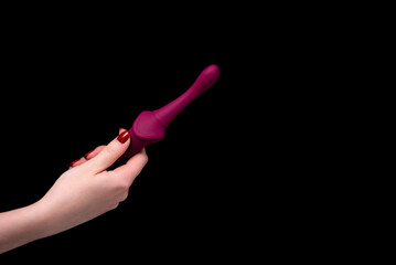 Burgundy stylish masturbation dildo in a girl's hand on a black background. Nozzle for penetration....