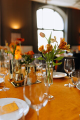 Cutlery, napkins, plates, flowers on an orange table. Table setting. Orange table decor