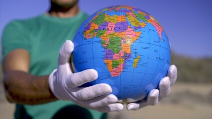 Save planet Earth, a young adult activist wears white gloves showing a globe. Concepts of global...