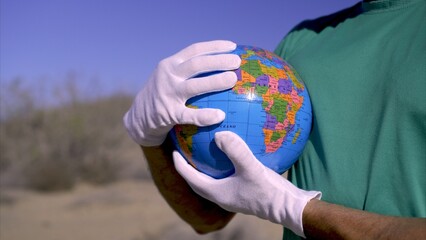 Protect planet Earth, an activist holds a globe while wearing white gloves. Concepts of saving the...