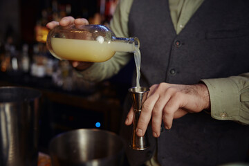Closeup of hand confident bartender male pouting liquor to make cocktail
