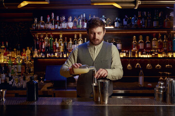 Confident bartender male pouting liquor to make cocktail