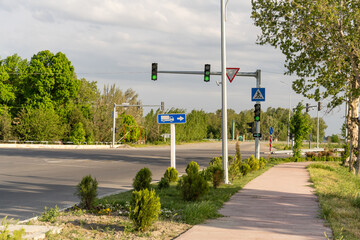 A street corner with a green arrow on a blue sign. The street is empty and there are no cars