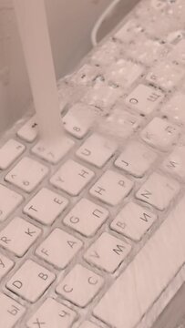 Woman washing white computer keyboard with a sponge with foam. Vertical video. 