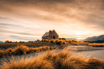Sunrise glowing over Church of the Good Shepherd and dry grass in autumn at Lake Tekapo, New Zealand