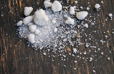 white crystals of table salt on a dark wooden background