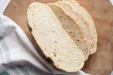 Overhead view of sliced artisan bread on wood chopping board, top view of baked sourdough artisan bread on wood background