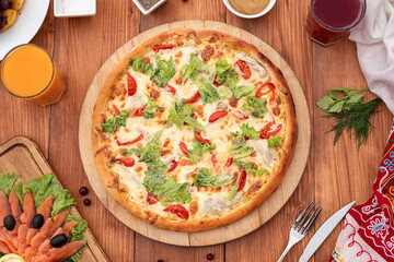 Caesar pizza on a set table, against the background of a wooden board, with cutlery, serving option