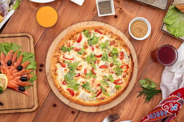 Caesar pizza on a set table, against the background of a wooden board, with cutlery, serving option
