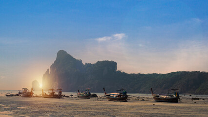 A view of long-tail boats lined up on the beach at dusk against the red sky. Stunning summer...