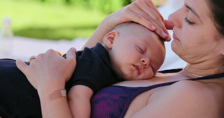 Candid Mother caressing baby infant by the swimming pool