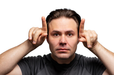 Young man making bull horn gesture on his head, portrait isolated on white background