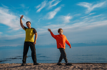 Happy father and son waving hands on lake shore