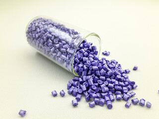 Violet pearl masterbatch granules in a glass tube on a white background, this polymer is a colorant...